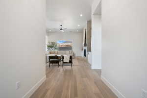Hallway with light wood-style floors and recessed lighting