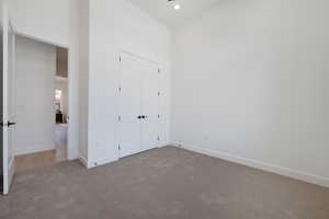 Unfurnished bedroom with carpet floors, a closet, recessed lighting, and a high ceiling