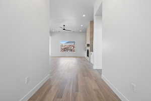Hall featuring baseboards, light wood-style floors, and recessed lighting