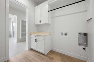 Laundry area with hookup for an electric dryer, hookup for a washing machine, cabinet space, baseboards, and light marble finish flooring