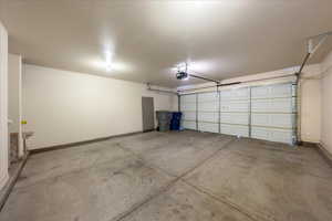 Garage featuring a garage door opener and baseboards
