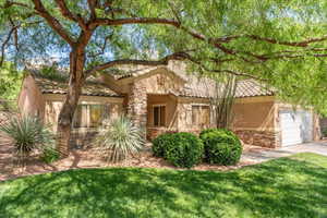 View of front of house with stone siding, stucco siding, a garage, and a front yard