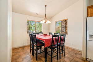 Dining area with a chandelier, vaulted ceiling, and baseboards