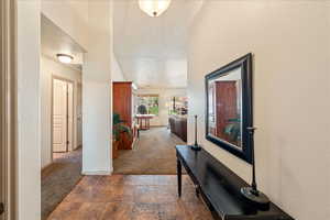 Hallway featuring carpet floors, baseboards, and stone finish floors