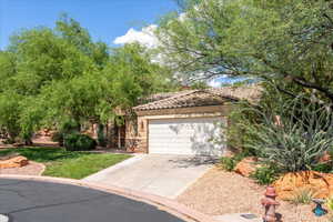 View of front of property with stone siding, driveway, a tiled roof, stucco siding, and a garage