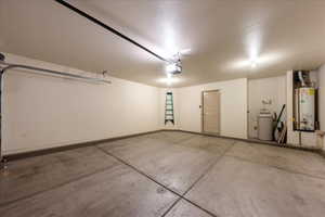 Garage featuring water heater, a garage door opener, and baseboards