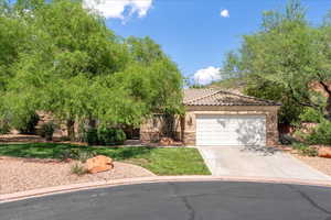 Obstructed view of property featuring an attached garage, driveway, a tiled roof, stucco siding, and stone siding