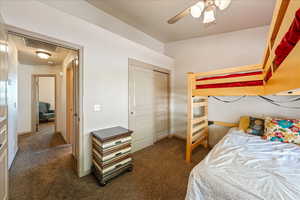 Carpeted bedroom featuring a closet and a ceiling fan