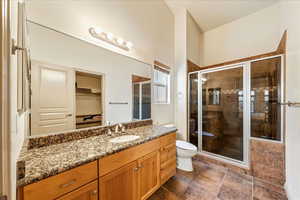 Bathroom featuring vanity, a stall shower, toilet, and a walk in closet