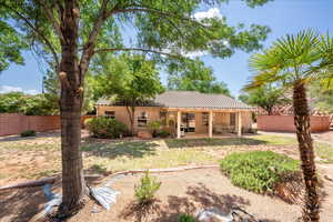 Back of property with a tile roof, stucco siding, and a patio
