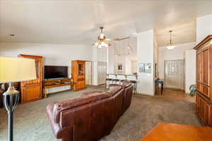 Living area with carpet floors, high vaulted ceiling, a ceiling fan, and baseboards