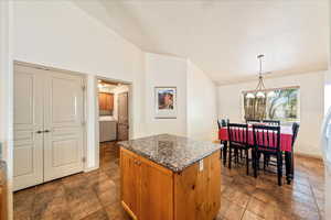 Kitchen with vaulted ceiling, washer / clothes dryer, a chandelier, a center island, and pendant lighting