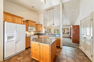Kitchen with white appliances, a kitchen island, rail lighting, a peninsula, and a ceiling fan
