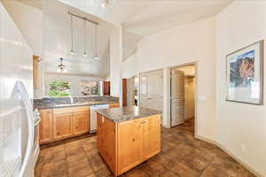 Kitchen featuring white appliances, a kitchen island, a sink, light brown cabinetry, and ceiling fan