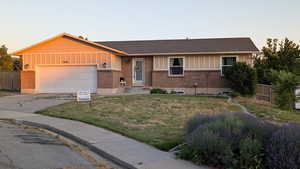 Single story home featuring a garage, driveway, board and batten siding, and brick siding