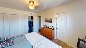 Bedroom featuring multiple closets, carpet, baseboards, and ceiling fan