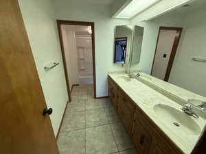 Full bath featuring double vanity, tile patterned flooring, and baseboards