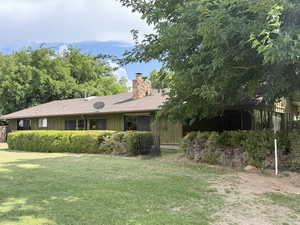 Rear view of property featuring a chimney, board and batten siding, and a yard