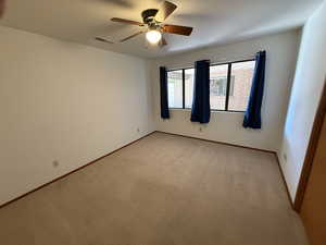 Empty room featuring ceiling fan, light carpet, and baseboards