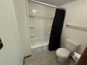 Bathroom featuring toilet and shower / tub combo with curtain