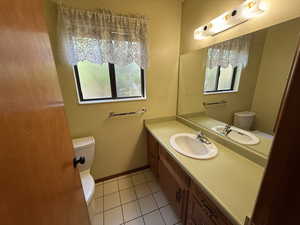 Half bathroom featuring toilet, tile patterned flooring, and vanity