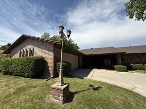 Single story home with driveway, a front yard, a garage, and stone siding