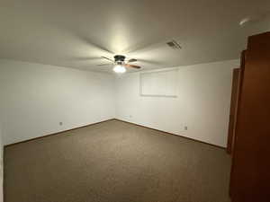 Spare room featuring a ceiling fan, dark carpet, and baseboards