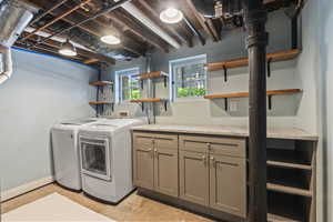 Laundry area featuring washer and clothes dryer, cabinet space, and baseboards