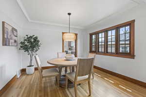 Dining area with light wood finished floors, baseboards, and crown molding