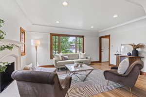 Living room featuring light wood finished floors, a high end fireplace, baseboards, recessed lighting, and crown molding