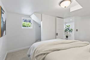 Carpeted bedroom with baseboards and a skylight