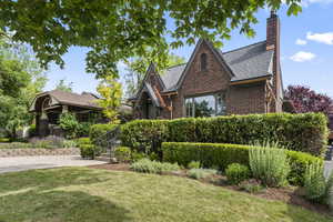 View of front facade with brick siding, a front lawn, and a chimney