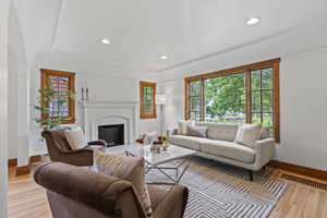 Living room featuring light wood-type flooring, baseboards, a fireplace, and recessed lighting