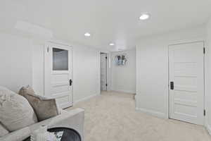 Living room with baseboards, light colored carpet, and recessed lighting