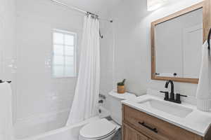 Bathroom featuring toilet, vanity, shower / bath combination with curtain, and ornamental molding