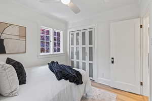 Bedroom with light wood finished floors, crown molding, and a ceiling fan