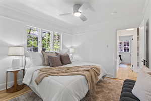 Bedroom with crown molding, light wood finished floors, ceiling fan, and baseboards