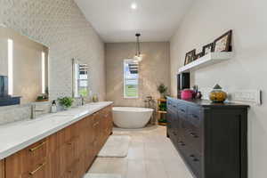 Full bathroom with a soaking tub, double vanity, tile patterned flooring, and wallpapered walls