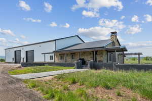 View of front of home featuring stone siding, driveway, metal roof, and covered porch
