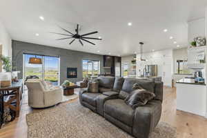 Living area featuring a ceiling fan, recessed lighting, a fireplace, and light wood-style flooring