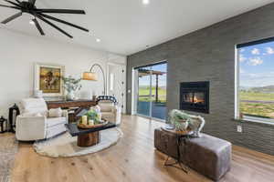 Living area with a fireplace, a ceiling fan, wood finished floors, recessed lighting, and an accent wall