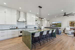 Kitchen with custom range hood, high end range, a sink, a kitchen bar, and open shelves