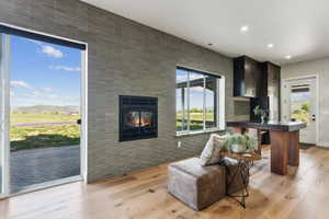 Living area with recessed lighting, a multi sided fireplace, and light wood-style floors
