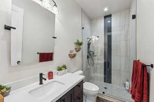Bathroom with vanity, toilet, a stall shower, and recessed lighting