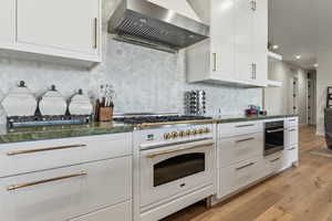 Kitchen featuring range hood, white stove, light wood-type flooring, oven, and white cabinets