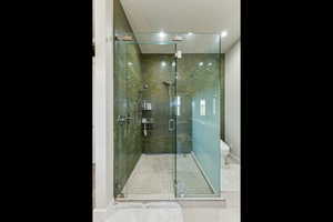 Bathroom featuring tile patterned flooring, toilet, a stall shower, and baseboards