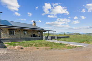 Rear view of property featuring a chimney, stone siding, metal roof, and a mountain view