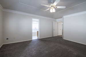 Spare room featuring carpet flooring, crown molding, ceiling fan, and baseboards