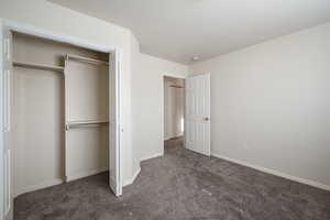 Unfurnished bedroom featuring carpet flooring, baseboards, and a closet