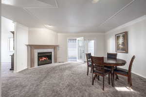Dining room featuring carpet floors, a tile fireplace, ornamental molding, and baseboards